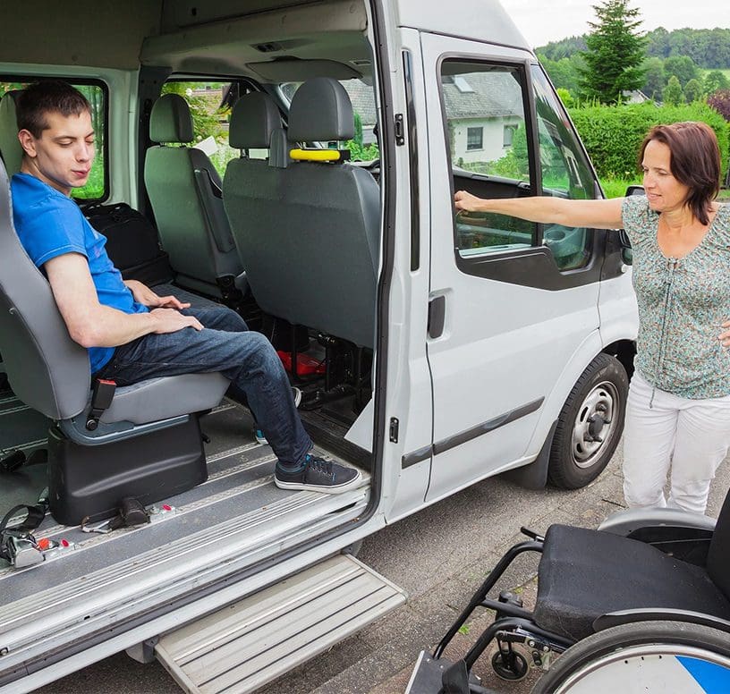 A woman in a wheelchair is standing next to a van.