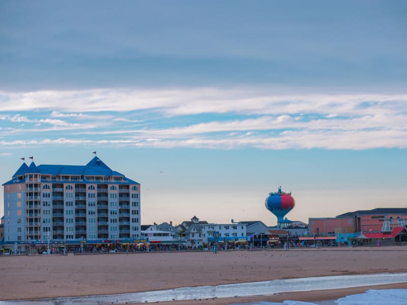 A beach with buildings and a hot air balloon in the sky.